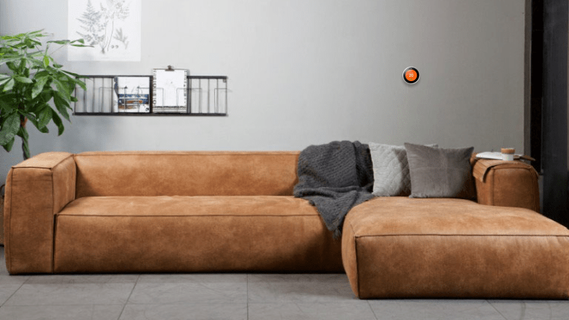 google nest aan de muur in de woonkamer met bruin leren bank